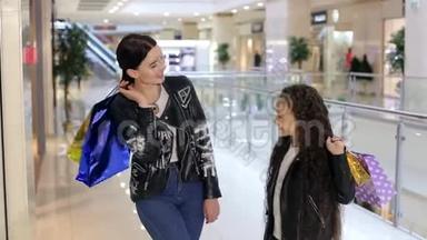 妈妈和女儿手里拿着袋子在商场里散步。